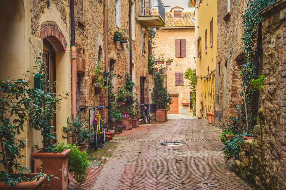 exploring a medieval tuscan town - cobblestone alley with flowers in windows
