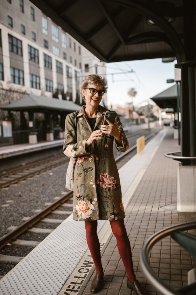 woman standing at a train stop video chatting.